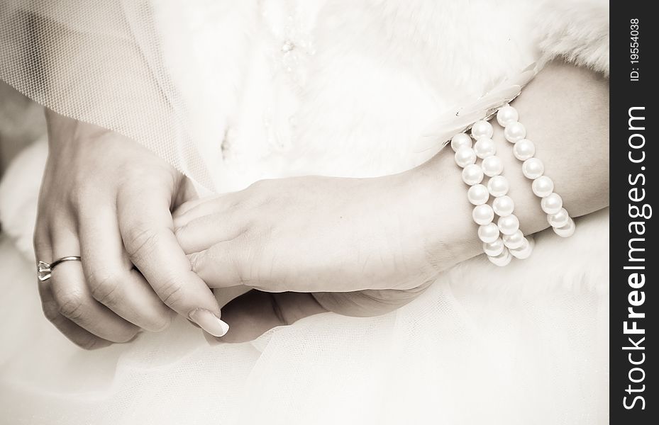 Bride's hands with ring and pearls