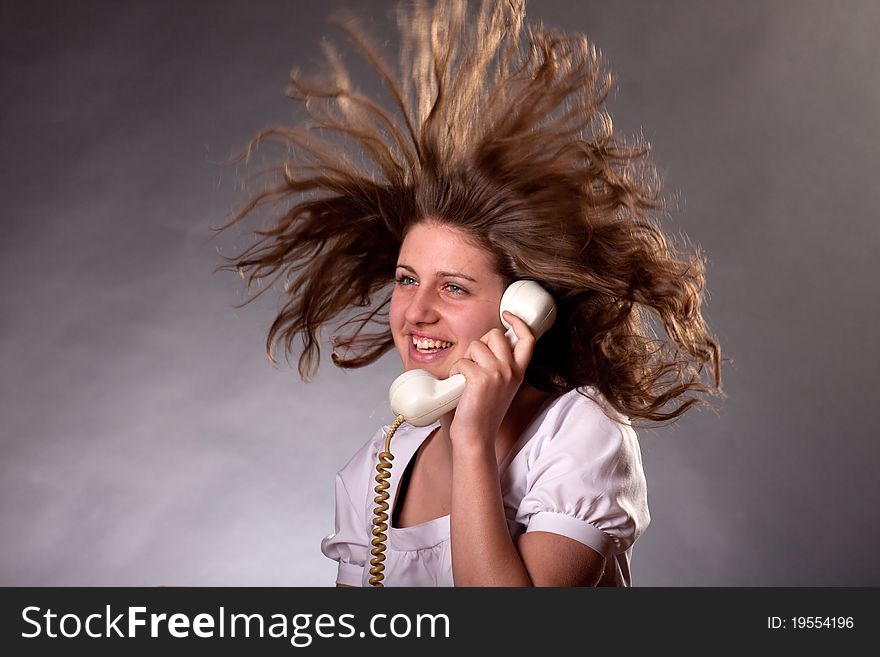 Woman talking on old phone with hair in the air. Woman talking on old phone with hair in the air