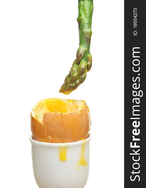 Asparagus spear dipped in the yolk of a soft boiled egg against white. Asparagus spear dipped in the yolk of a soft boiled egg against white