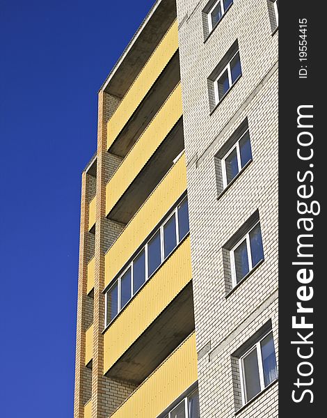 High building with a yellow facade against the blue sky. High building with a yellow facade against the blue sky