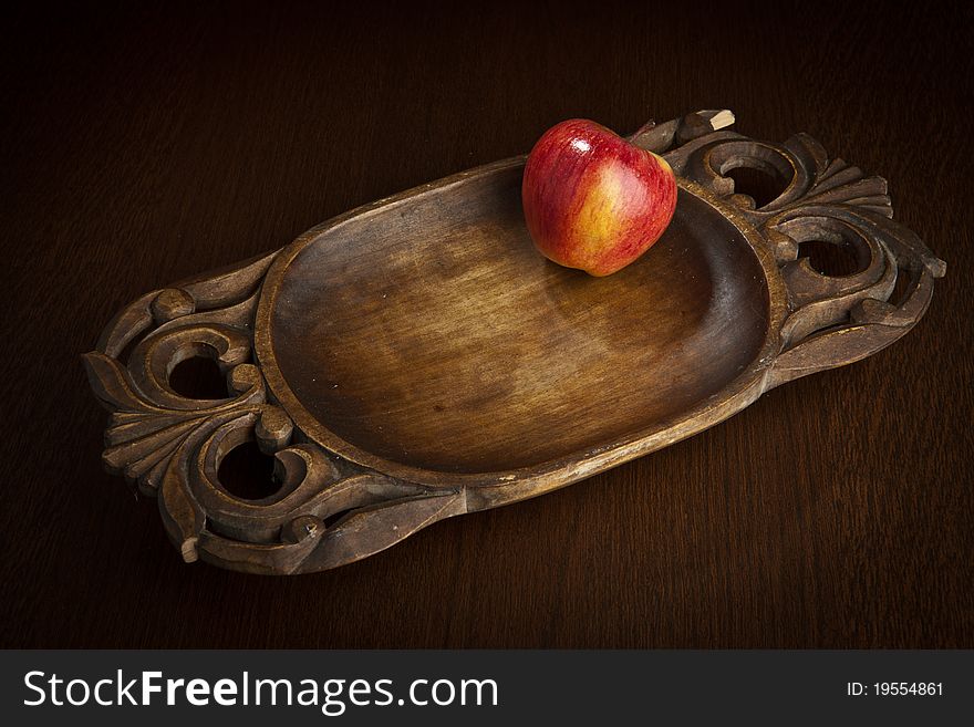 Brightly red apple on an ancient wooden dish. Brightly red apple on an ancient wooden dish