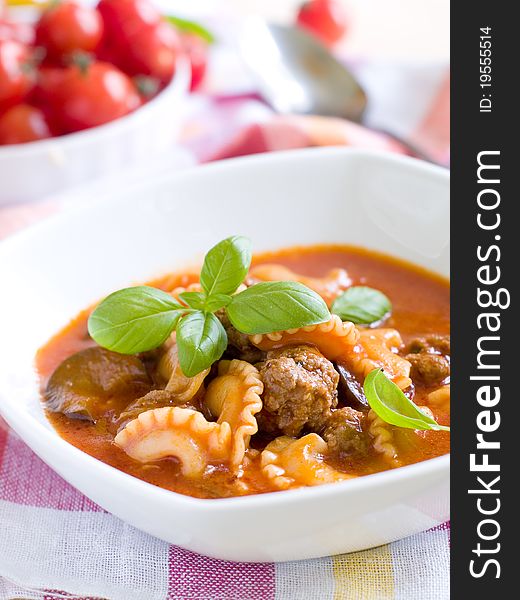 A bowl of tomato soup with pasta and minced meat ball