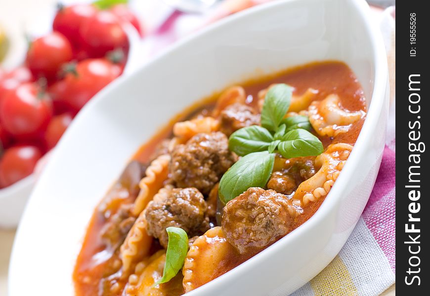 A bowl of tomato soup with pasta and minced meat ball