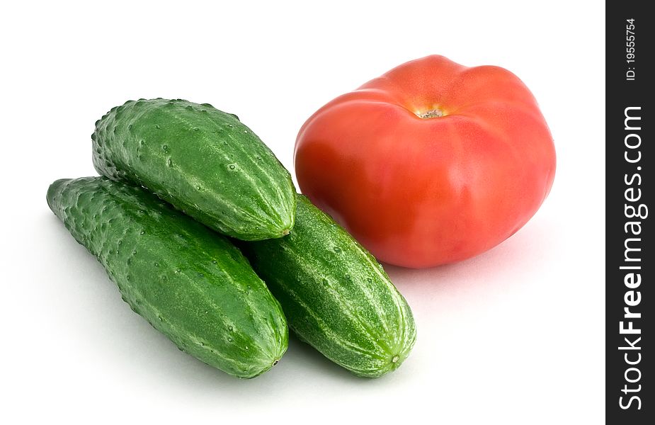 Three cucumbers and tomato isolated on white background