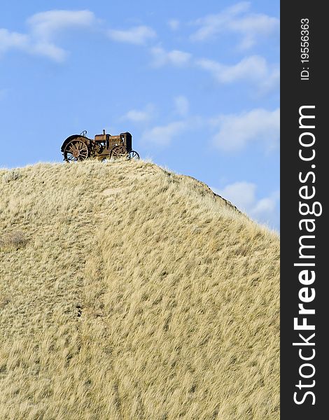 A rustic tractor sitting on the top of a grassy hill in Montana.