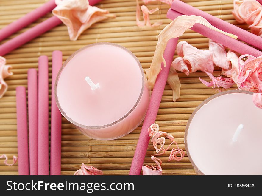 Spa treatment in bright pink and white palette, petals, candles, and arotatizirovannye sticks on a wooden bamboo rug