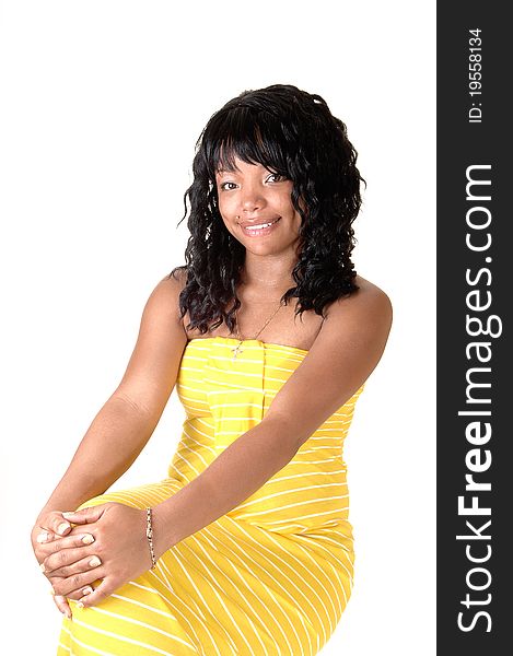 A beautiful African-American woman in a long yellow dress and dark black hair sitting on a chair, for white background. A beautiful African-American woman in a long yellow dress and dark black hair sitting on a chair, for white background.