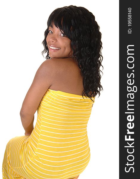 A beautiful African-American woman in a long yellow dress and dark black hair sitting from the back looking over shoulder, on white background. A beautiful African-American woman in a long yellow dress and dark black hair sitting from the back looking over shoulder, on white background.