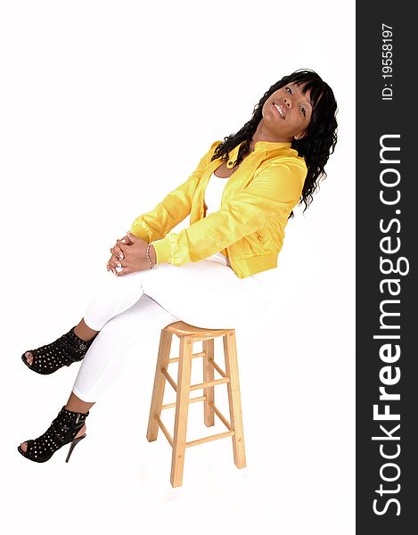 A young pretty African American woman sitting on an chair in white tights and a yellow jacket from the back, for white background. A young pretty African American woman sitting on an chair in white tights and a yellow jacket from the back, for white background.