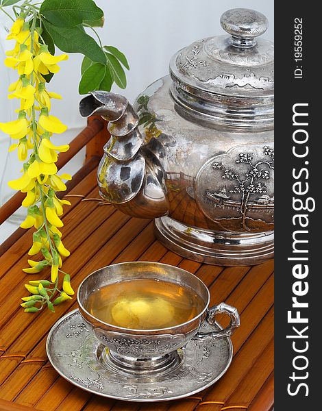 Green tea in a cup, flowers, yellow acacia on a bamboo tray. Green tea in a cup, flowers, yellow acacia on a bamboo tray