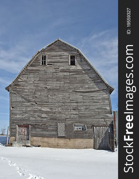 Barn in Wisconsin during winter with snow on the ground and scattered clouds in sky. Barn in Wisconsin during winter with snow on the ground and scattered clouds in sky.