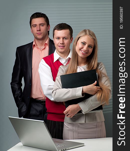 Two men and woman working with a computer in the office