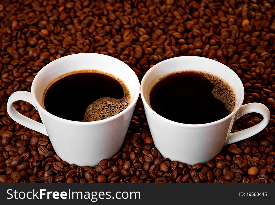 Two cups of coffee on roasted coffee beans. Two cups of coffee on roasted coffee beans