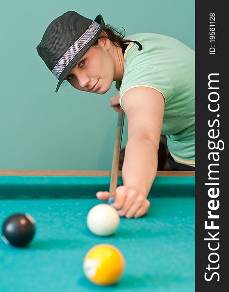 Young woman in hat playing billiards. Young woman in hat playing billiards