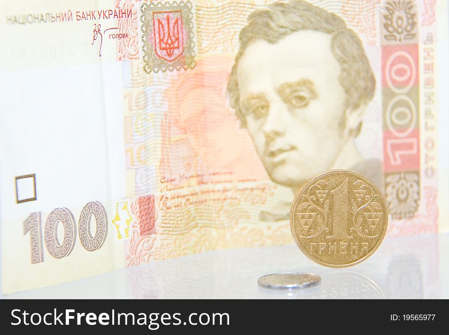Kopek and hrivna coins against one hundred bill