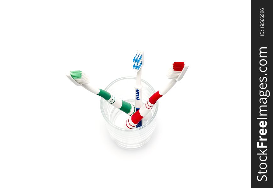 Colorful toothbrushes in a glass over white