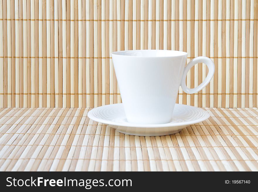 White empty cup and saucer on bamboo background