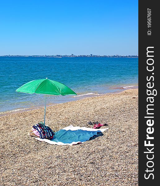 Green umbrella, clothes and things on a beach. Green umbrella, clothes and things on a beach