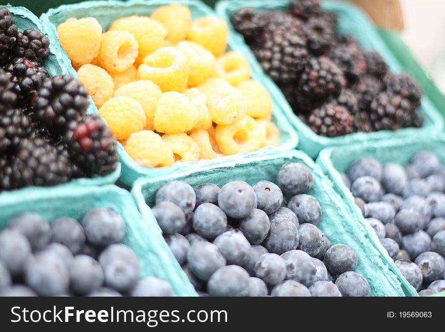 Display of Bright yellow berries surrounded by blackberries and blueberries