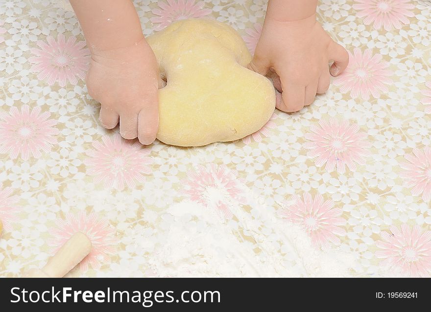 Child's hands kneading dough on table