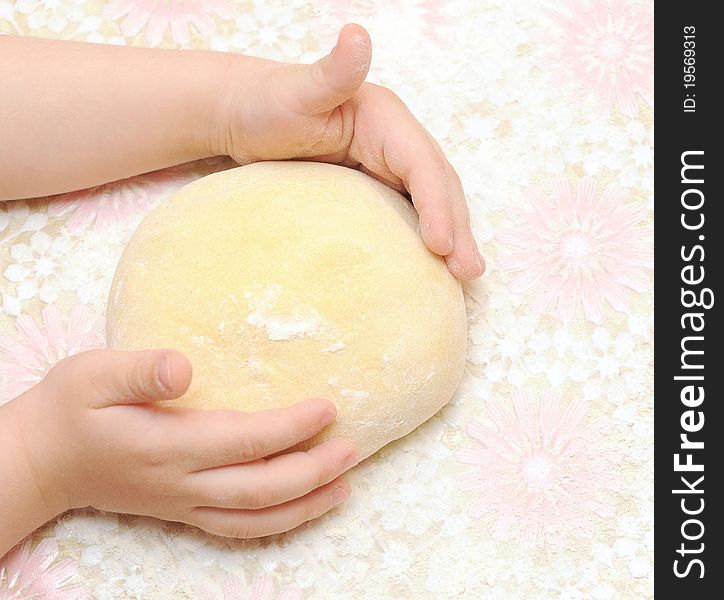 Child's hands kneading dough on table