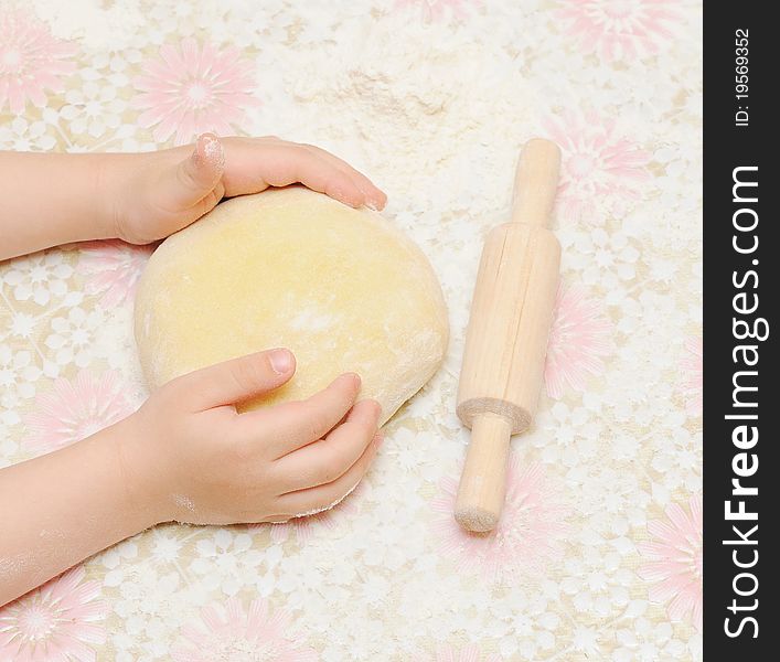 Child's hands kneading dough on table