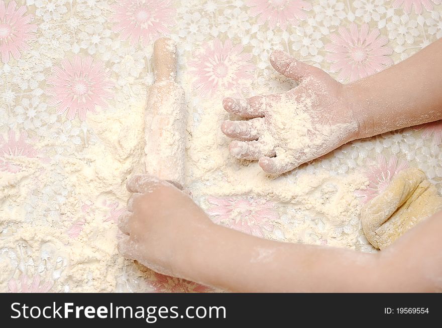Child's hands kneading dough on table