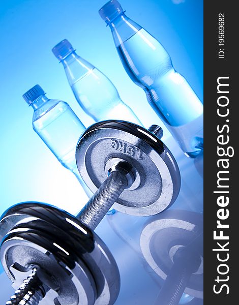 Dumbells and bottles of water on the blue background