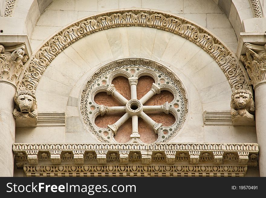 An ornate arch and circular stone carving over the door of the cathedral in Lucca, Italy. An ornate arch and circular stone carving over the door of the cathedral in Lucca, Italy