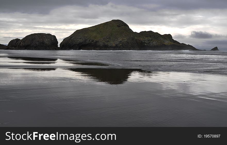 Low tide on the Oregon Coast, storm coming in from the ocean. Awesome reflection of the rocks in the wet sand. Low tide on the Oregon Coast, storm coming in from the ocean. Awesome reflection of the rocks in the wet sand