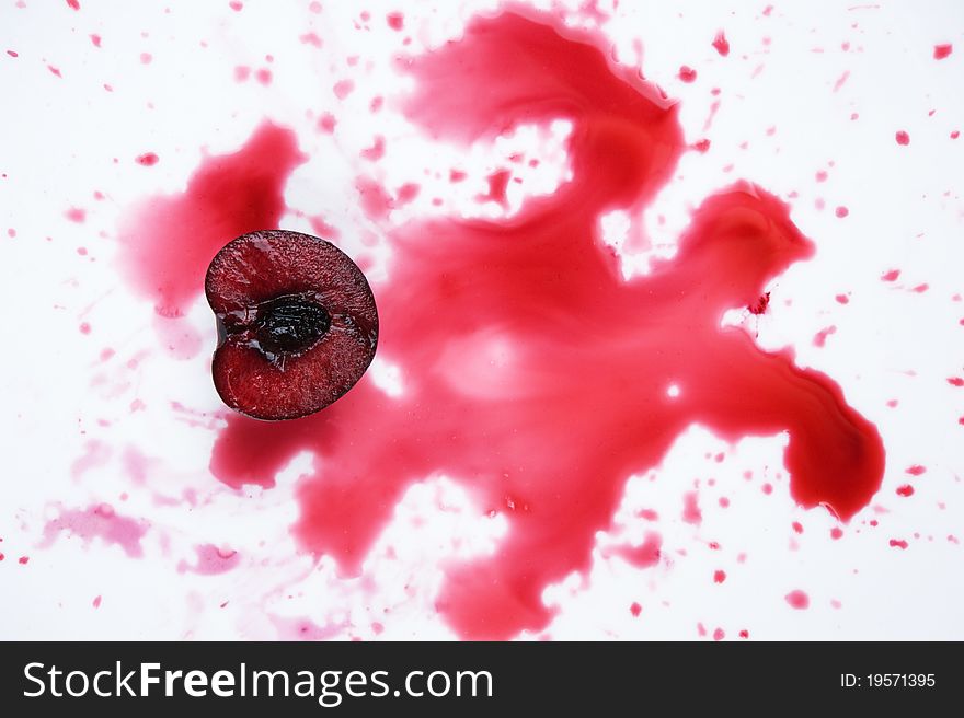 Image of fresh cherry cut in halves with  cherry juice on white