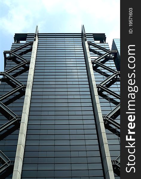 Front upward view of a high-rise glass and metal structure commercial building with stylish zigzag steel decorations on sides. Front upward view of a high-rise glass and metal structure commercial building with stylish zigzag steel decorations on sides