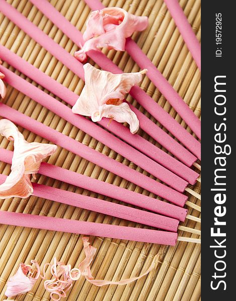 Spa treatment in bright pink and white palette, petals, and arotatizirovannye sticks on a wooden bamboo rug
