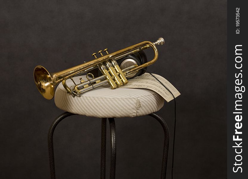 Trumpet, headphones and music on stool. Trumpet, headphones and music on stool