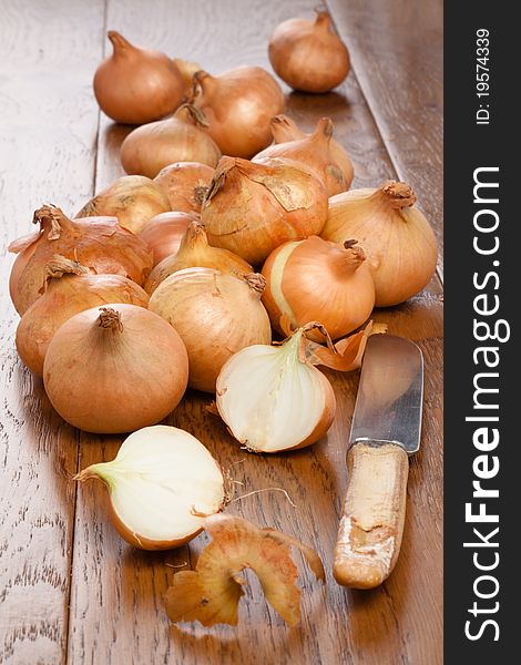 Small onions on a wooden table one half cut with a knife