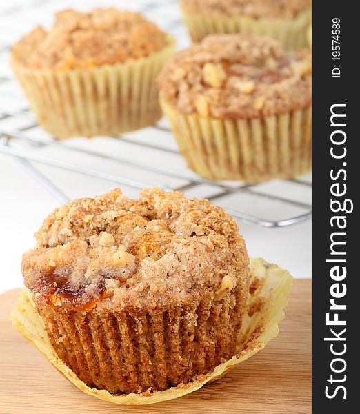 One coffee cake muffin with muffins in background on cooling rack
