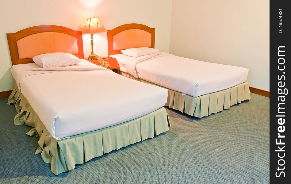 Twin generic white bed with lamp between them. Twin generic white bed with lamp between them