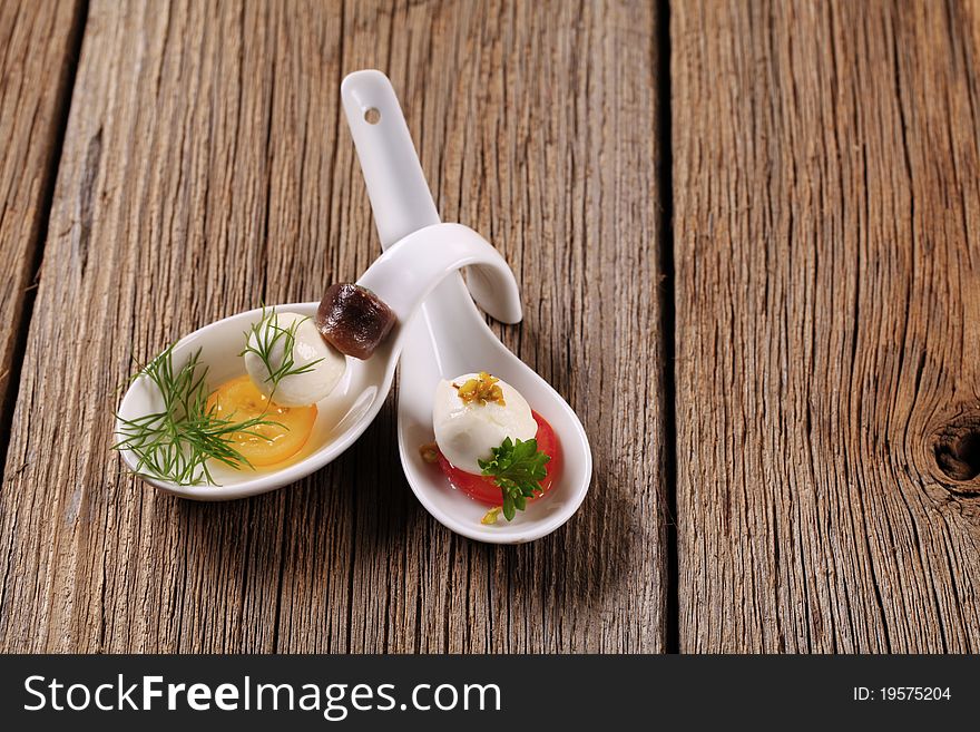 Mozzarella cheese snacks on porcelain spoons - closeup. Mozzarella cheese snacks on porcelain spoons - closeup