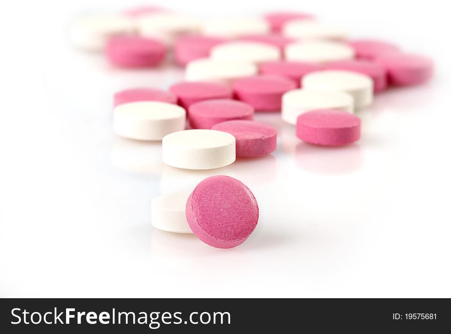 White and pink pills on white background