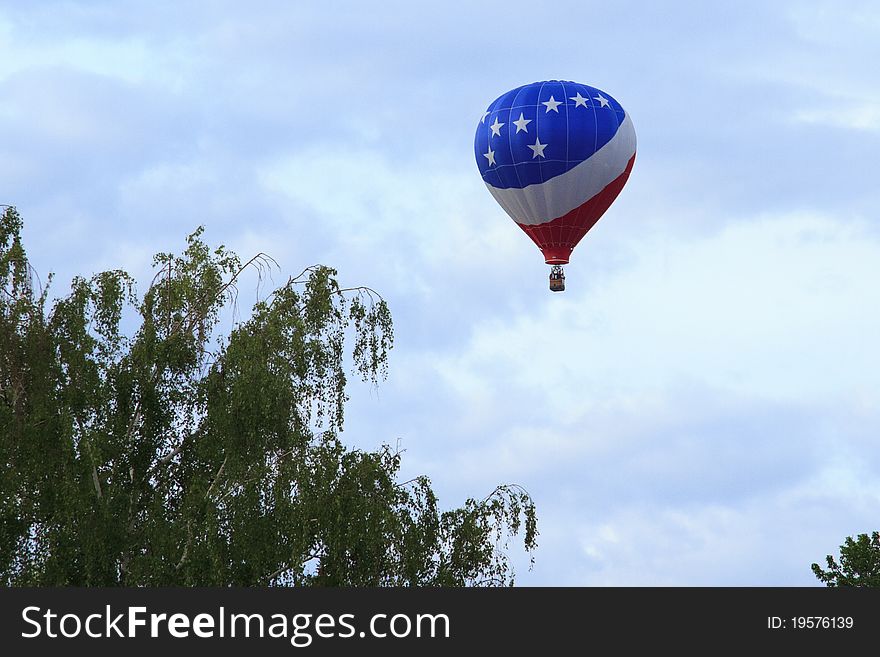 Red, White and Blue hot air balloon taking off over eastern washington and flying over trees. Red, White and Blue hot air balloon taking off over eastern washington and flying over trees