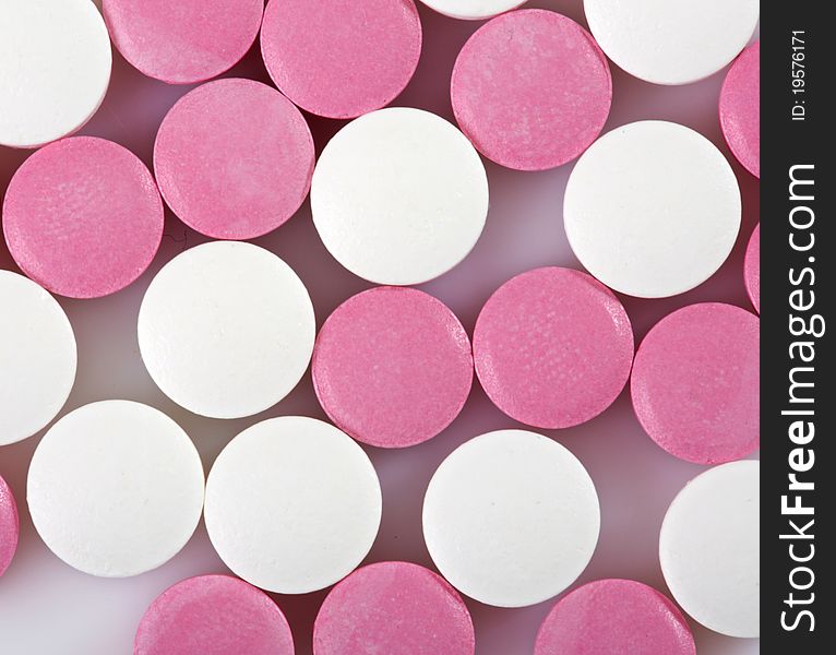 Pink and white pills on white background