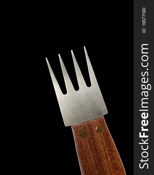 A steel fork with wooden handle on black background. A steel fork with wooden handle on black background