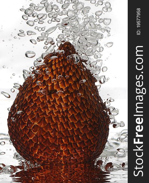 A macro shot of the tropical fruit salak aka snakeskin fruit under water with bubbles rising. A macro shot of the tropical fruit salak aka snakeskin fruit under water with bubbles rising.