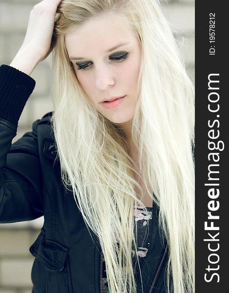 Blond young girl in black jacket and with black eyes looking somewhere. Blond young girl in black jacket and with black eyes looking somewhere