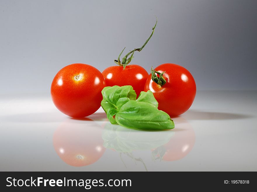 Three red tomato with a basil leaf. Three red tomato with a basil leaf