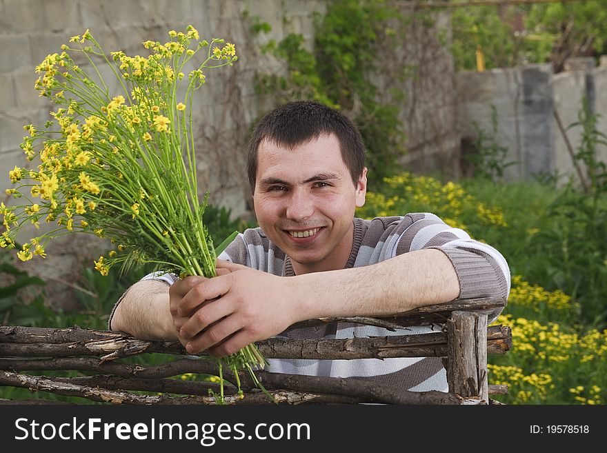 A young man awaits his girlfriend with a bouquet of yellow flowers