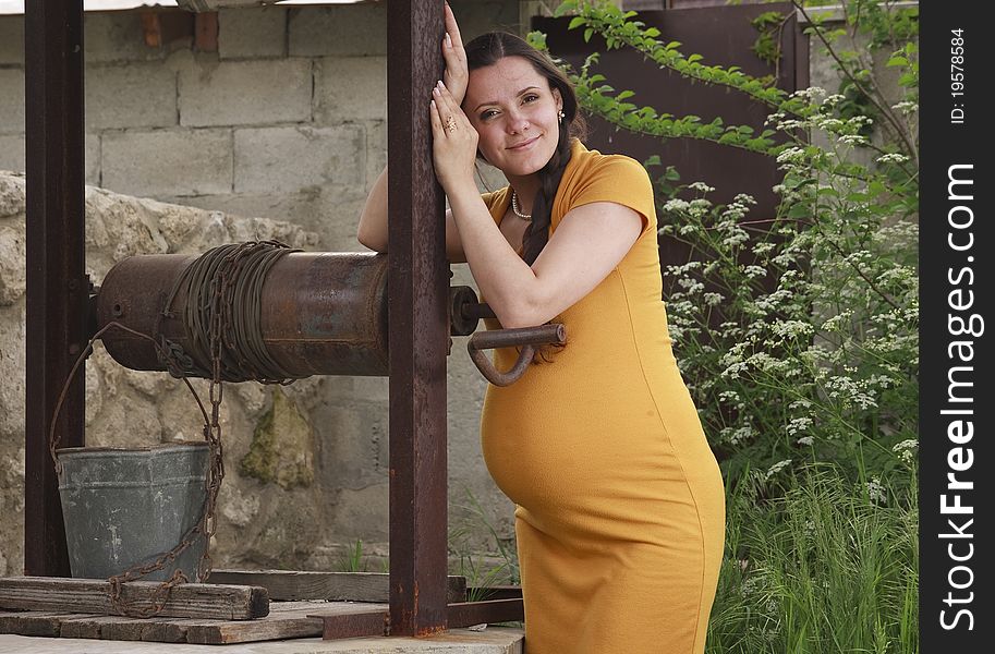 A happy pregnant woman is resting in the garden