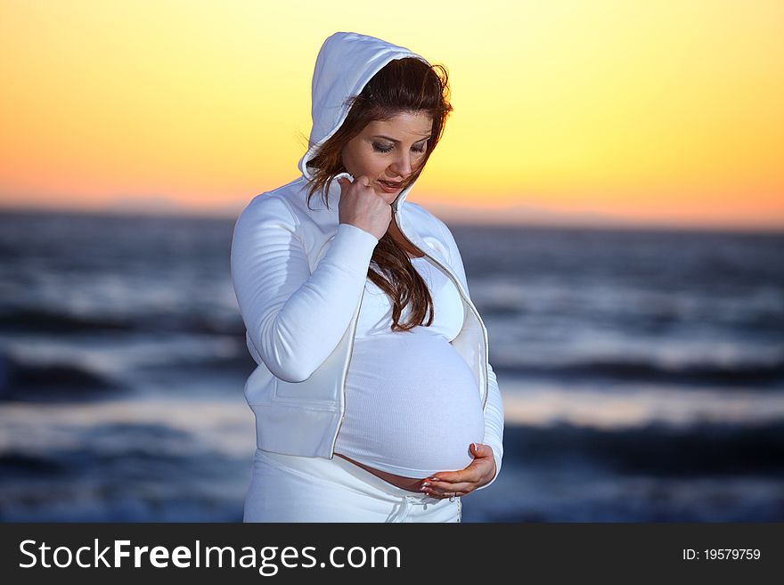 Pregnant woman at the Beach with jacket and hood