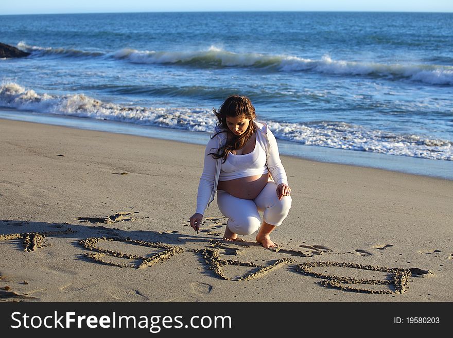 Pregnant Woman At Beach Writing  Baby In The Sand