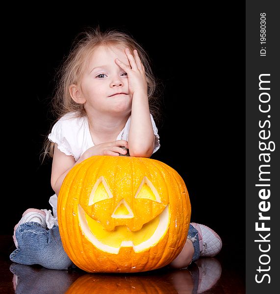 An adorable child is holding her pumpkin trying to make the same face as it. An adorable child is holding her pumpkin trying to make the same face as it.